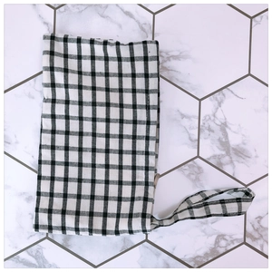 Detailed top view of a black and white checkered fabric pouch with a side handle strap