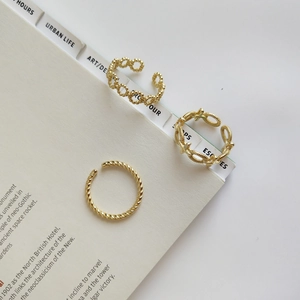 Close-up of a three-piece gold twisted, beaded, and crossed ring set on a book