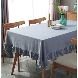 Close-up of gray-blue cotton tablecloth with ruffled edges on a wooden dining table