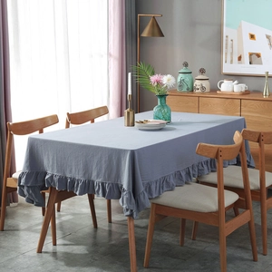 Blue-gray cotton table cloth with ruffled edges on a wooden table in a Nordic style room