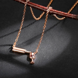 Macro shot of rose gold wine bottle necklace with a sparkling red heart zircon gem