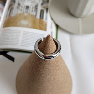 Minimalist silver ring displayed on a wooden cone stand with a modern lifestyle background