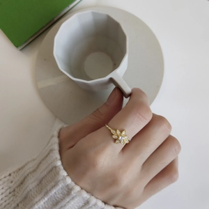 Close-up of elegant gold flower ring with sparkling crystals worn on hand by coffee cup