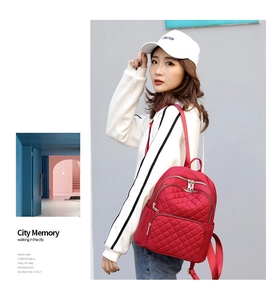Red quilted nylon backpack for women styled with a casual outfit in a city setting