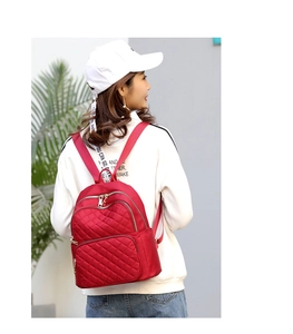 Rear view of a model wearing a red quilted nylon backpack with gold metal zippers