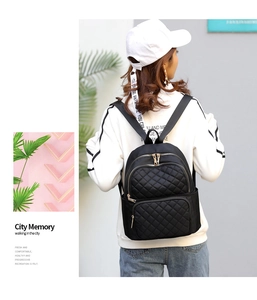 Detail of black quilted nylon backpack with gold zippers and side pockets for travel