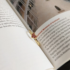 Detail of a heart-shaped gold ring with red stones placed inside a book page