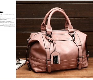 Detail of pink faux leather Boston bag with metallic hardware on a wooden table