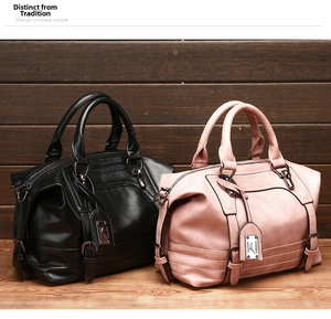 Detail view of black and pink soft Boston handbags with dual handles and leather texture
