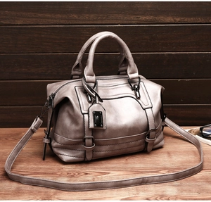 Detailed shot of taupe leather Boston bag featuring double handles and metal nameplate