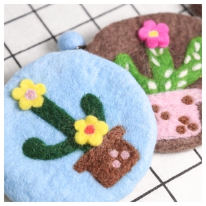 Handmade wool felt cactus coin purse with colorful floral details on checkered background
