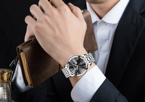 Close-up of a silver business watch on wrist with Roman numerals and day-date display