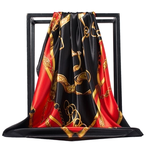 Detail of red and black silk scarf with gold chain pattern on a minimalist black frame