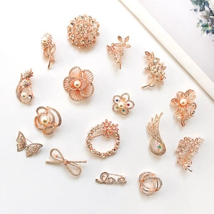 Détail de l'ensemble de broches en or rose avec strass brillants et perles blanches variées