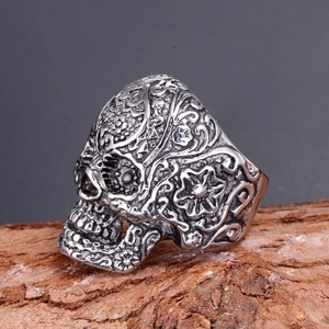 Macro shot of vintage skull ring with intricate floral carvings on rustic bark