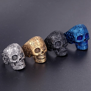 Detail showing four gothic skull rings in silver, gold, black, and blue finishes