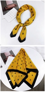 Detail of a bright yellow silk scarf with black camellia floral patterns and silk texture