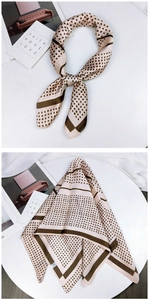 Detailed view of beige and dark brown polka dot silk scarf tied and folded on table