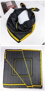 Detail of a black and yellow silk scarf with geometric border and polka dot patterns