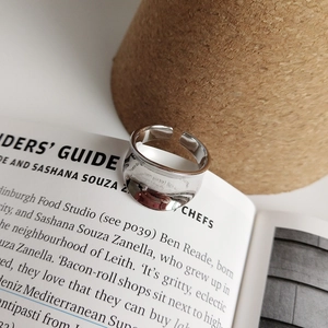 Minimalist silver wide irregular ring placed on an open book for a modern aesthetic look