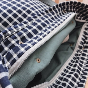 Detail of checkered canvas tote featuring navy pattern, green lining, and secure zipper