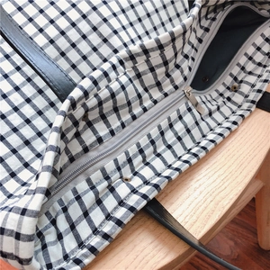 Close-up of smooth metal zipper and reinforced rivets on the plaid cotton tote bag