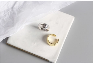 Minimalist double-layered S925 silver rings in gold and silver finish on a ceramic tray