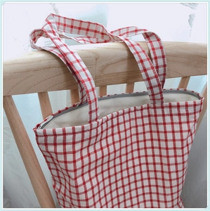Détail du cabas en coton vichy rouge avec fermeture éclair et bandoulière large
