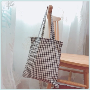 Détail du sac cabas japonais en toile à damier noir et blanc sur une chaise en bois