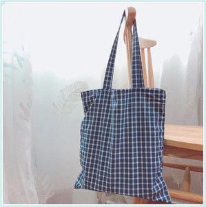 Détail d'un sac cabas en coton à carreaux bleu et blanc sur une chaise en bois