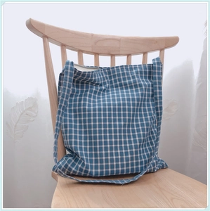 Gros plan du sac fourre-tout en toile à carreaux bleu et blanc sur une chaise