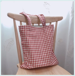 Détail du sac cabas en toile à carreaux rouges et blancs sur une chaise en bois