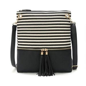 Detailed view of striped crossbody bag with black faux leather and twin tassel zippers