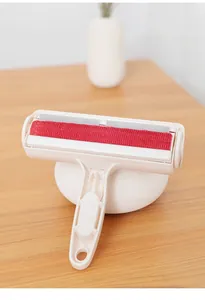 Gros plan du rouleau anti-poils pour animaux avec tissu rouge et poignée en plastique blanc