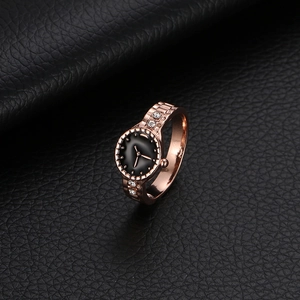Macro detail of rose gold watch-shaped ring with black dial and white rhinestones