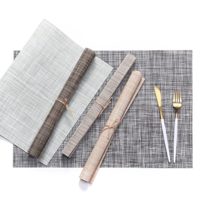 Set of woven PVC placemats in grey and beige with cutlery on a white background