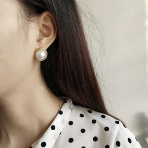 Macro shot of 925 sterling silver pearl stud earrings worn by a model in French vintage style