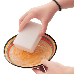 White nano magic sponge block cleaning a greasy plate with foam on white background