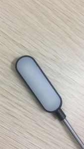 Detail of black USB LED light with flexible metal hose on a light wood desk