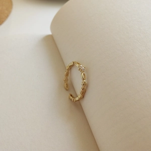 Detail eines goldenen verstellbaren Rings mit Blütenstruktur und weißen Zirkonias
