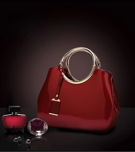 Close-up of deep red patent leather bridal bag with elegant golden metal ring handles