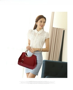 Close-up of red patent leather bridal bag with elegant golden circular metal handle