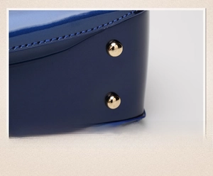 Close-up of golden protective studs on the blue patent leather bag base for durability