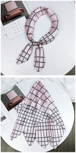 Detailed flat lay of a pink checkered silk scarf with red dots on a white table