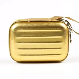 Miniature gold suitcase storage box with brushed metallic finish and secure dual zippers