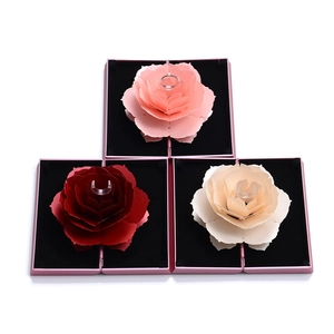 Detailed view of three rotating rose ring boxes in red, pink, and beige with 3D petals