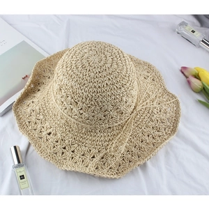 Chic beige woven straw hat with wide wavy brim and bow decoration on white background
