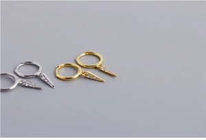Detailed view of silver and gold geometric triangular hoop earrings with pavé crystals