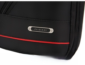 Close-up of waterproof black oxford cloth with metal logo and red contrast stitching detail