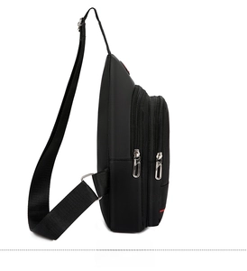 Side view of black nylon crossbody bag featuring double zippers and metal hooks